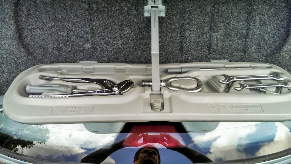 Car trunk tool kit with pliers, screwdriver, tow hook, and wrenches