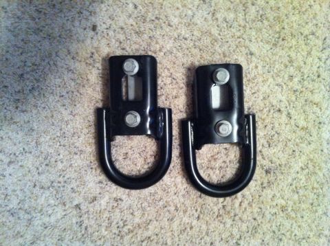 1982 Ford Bronco - Two black tow hooks with D-rings are shown against a carpeted background.
