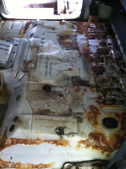 1992 Ford Bronco - The interior floor pan shows significant rust damage and wear, with exposed metal and mounting hardware visible.
