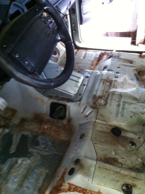 1992 Ford Bronco - The interior floor of this vehicle is heavily rusted and appears to be undergoing restoration or has been stripped.