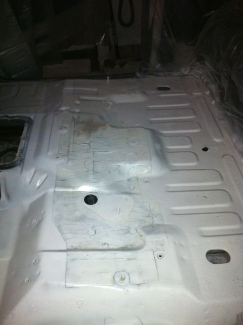 1992 Ford Bronco - The bare metal floor pan of a vehicle interior, revealing its underlying structure and various holes for mounting components.