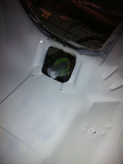 1992 Ford Bronco - The floor of a vehicle interior shows a hole with visible mechanical components beneath the white paint.
