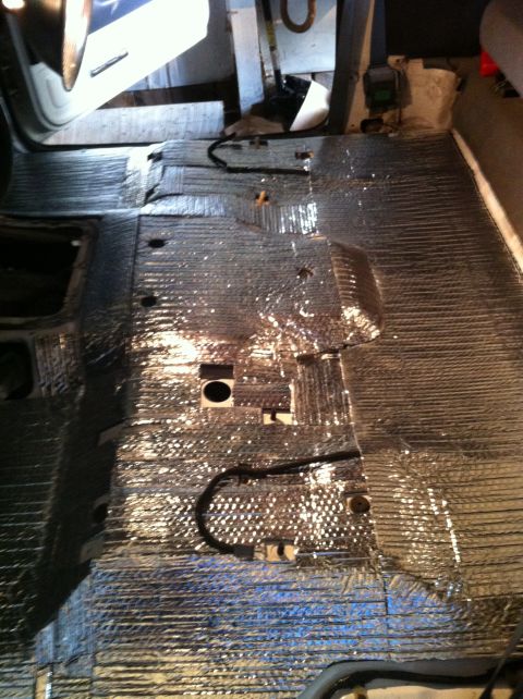 1992 Ford Bronco - The interior floor of a vehicle is covered in silver insulation material with visible wiring and mounting points.