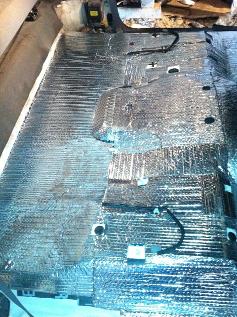 1992 Ford Bronco - The interior floor of a vehicle is covered in reflective insulation material, obscuring the original flooring and components.