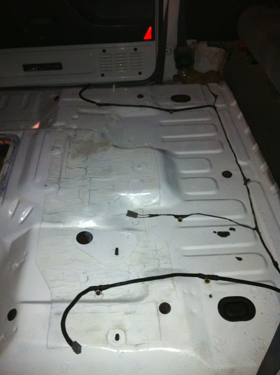 Interior floor of a vehicle with exposed wiring. A label reads 'F150'