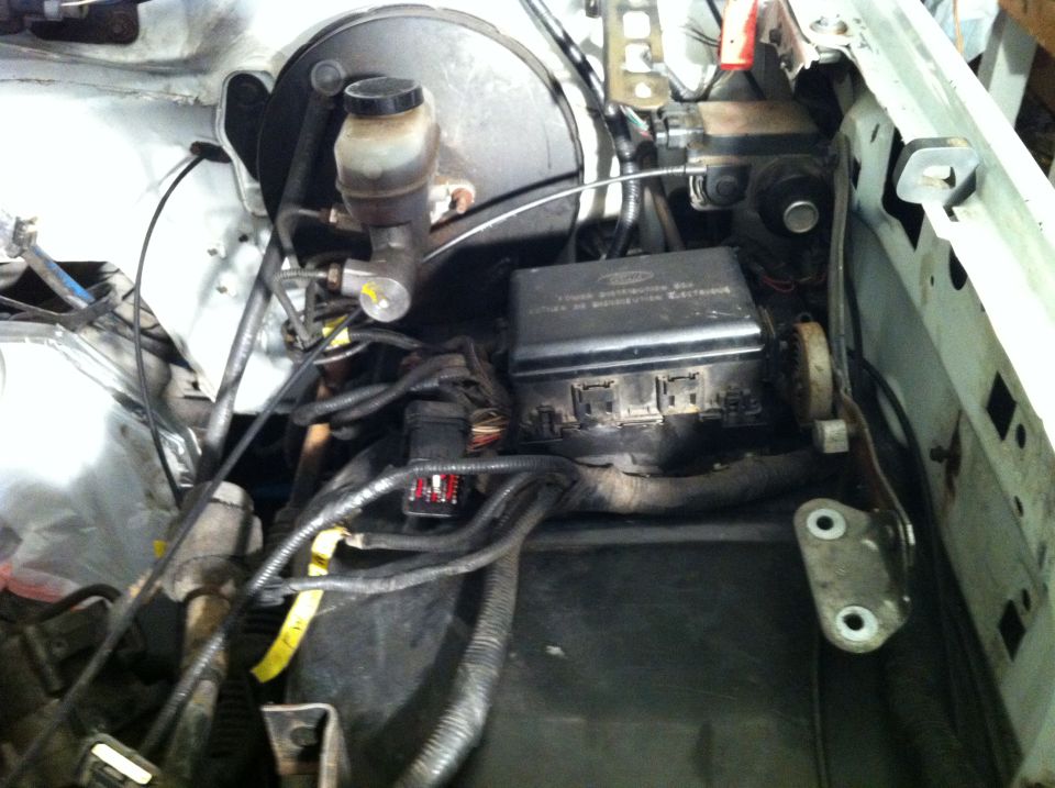 Engine bay with brake fluid reservoir and fuse box visible. Lots of wires and hoses