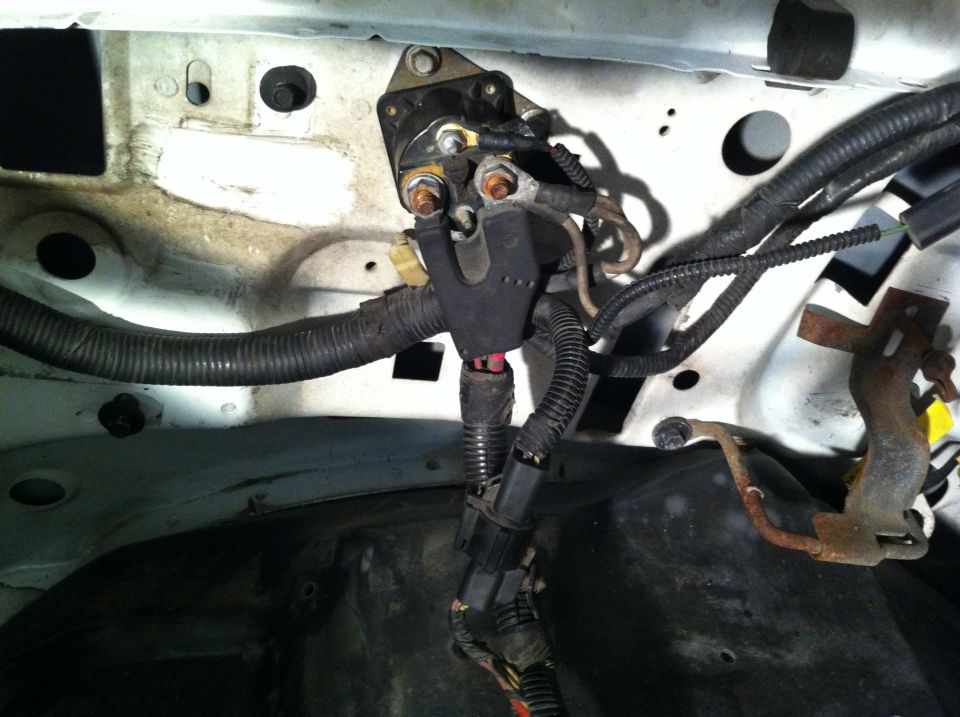 Engine bay wiring harness and starter solenoid with visible rust on mounting bracket