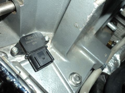 2004 Mercury Grand Marquis - Close-up of a Ford sensor with visible part number and date, attached to an engine part.