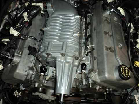 2004 Mercury Grand Marquis - Close-up of a silver supercharger installed on an engine, Ford branding on the valve cover.