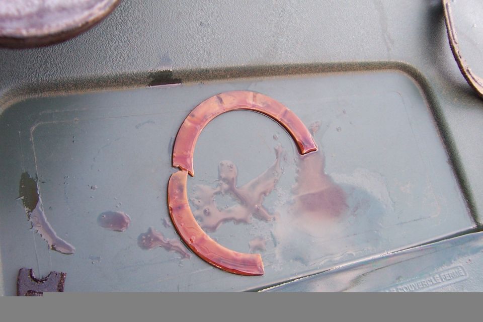 Broken copper washer in a tray with some fluid