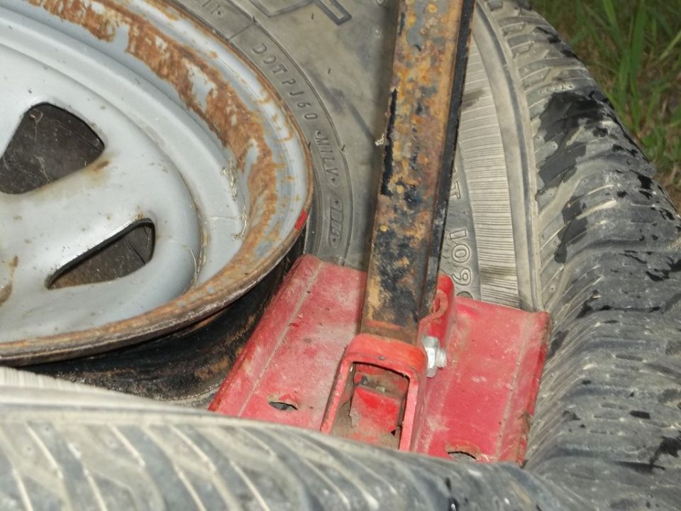Car jack resting on tires, with visible rust on the jack and wheel rim