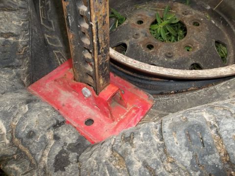 1995 Ford Bronco - A red hi-lift jack is positioned on a pair of tires, with a spare wheel in the background.