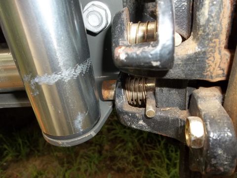 1995 Ford Bronco - Detail of a mechanical component, showing wear and tear on a metal cylinder and a spring-loaded latch.