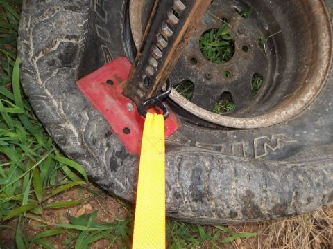 1995 Ford Bronco - A flat tire is secured by a jack and a yellow tow strap, indicating a need for roadside assistance.