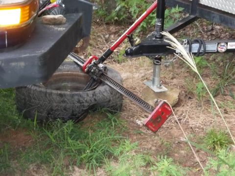 1995 Ford Bronco - A hi-lift jack is being used to lift a vehicle tire, with a trailer hitch in the background.
