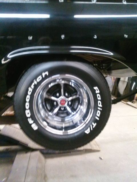 1960 Ford Falcon - A close-up view of a car's rear wheel and fender, showing aftermarket chrome wheels and tires.