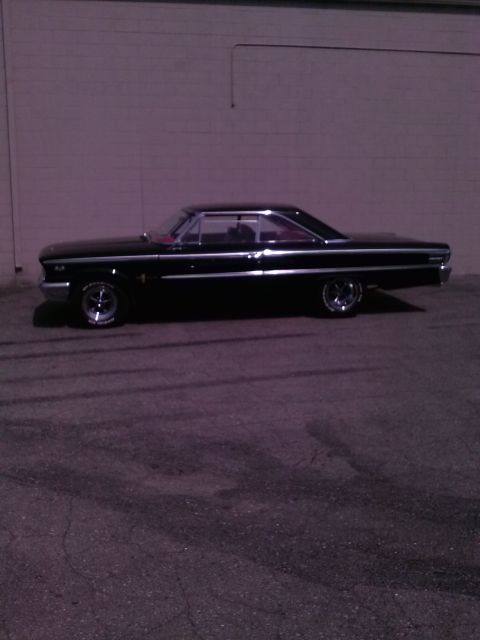1960 Ford Falcon - Side view of a black coupe with chrome accents parked near a brick wall.
