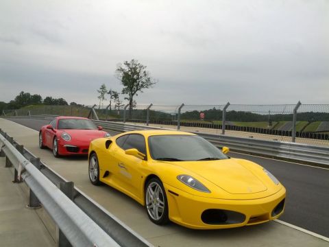 1979 Ford F-150 - Two sports cars, a yellow Ferrari and a red Porsche, on a racetrack under a cloudy sky.