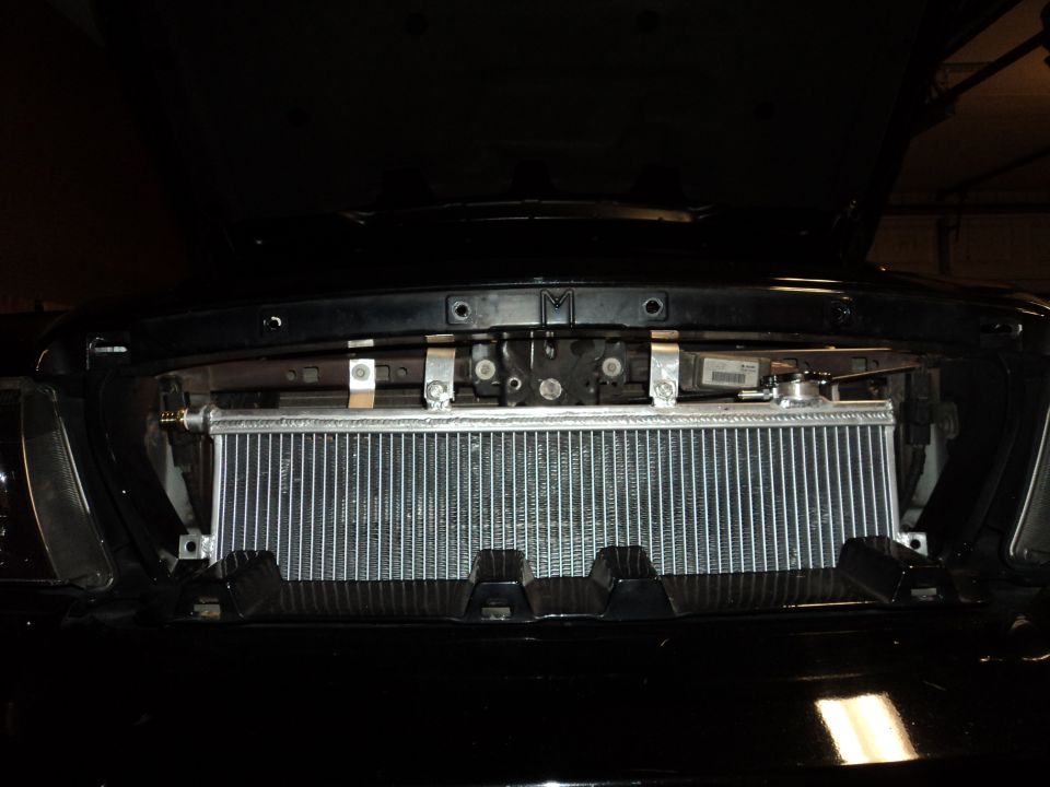 Aftermarket radiator installed in front of vehicle grille