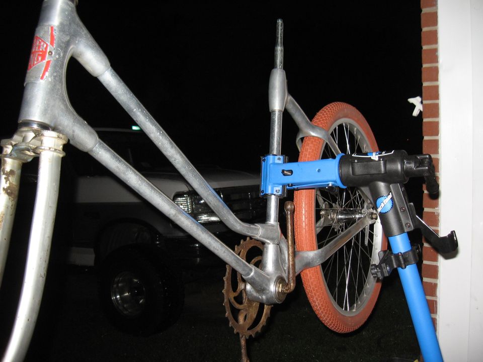 Aluminum bicycle frame with orange tire on repair stand