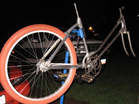 1994 Ford Bronco - A bicycle frame with an orange tire is mounted on a stand, with a vehicle visible in the background.