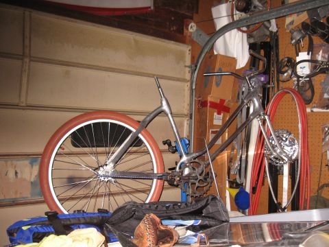 1994 Ford Bronco - A custom bicycle is partially assembled in a cluttered garage, with tools and parts visible in the background.