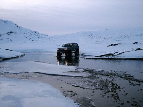 1996 Ford Bronco - A 1996 Ford Bronco navigates a frozen stream in a snow-covered, mountainous terrain.