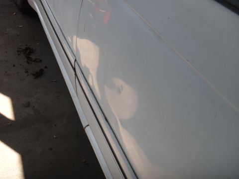 1990 Ford Taurus - Side view of a white car door showing a dent and body trim.