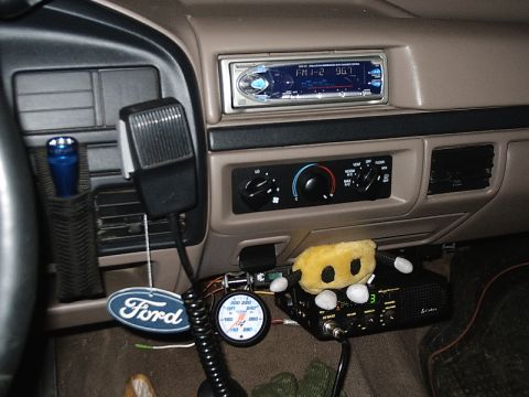 1996 Ford Bronco - The interior of a Ford truck features a CB radio, microphone, and a gauge, along with a plush toy.