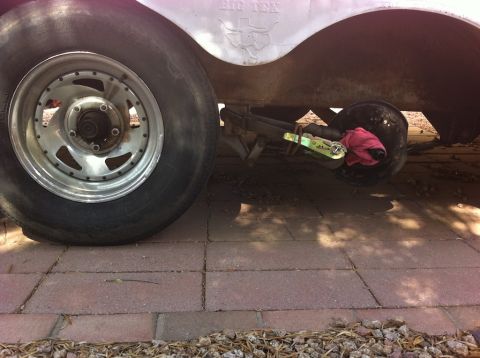 1999 Ford F-250 - Close-up of a trailer's wheel, axle, and brake assembly, showing a pink rag tied around the brake drum.