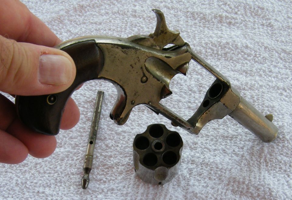 Disassembled revolver with cylinder removed, held by a hand