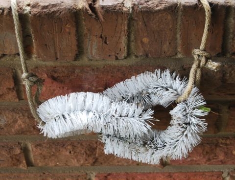 1975 Ford Ranchero - Two white bottle brushes are tied together with rope and suspended against a brick wall.