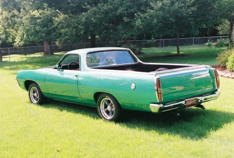 1971 Ford Ranchero - This green pickup truck, likely from the 1970s, is shown from the rear with a distinctive white stripe on its tires.