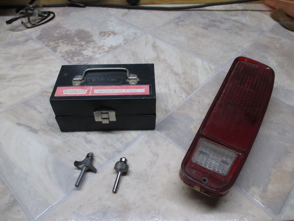 Craftsman router bit kit and a red tail light assembly on a tiled floor
