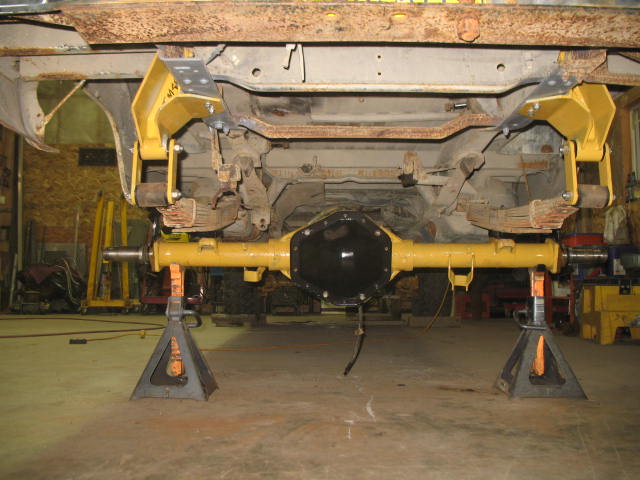 Yellow painted rear axle assembly on jack stands