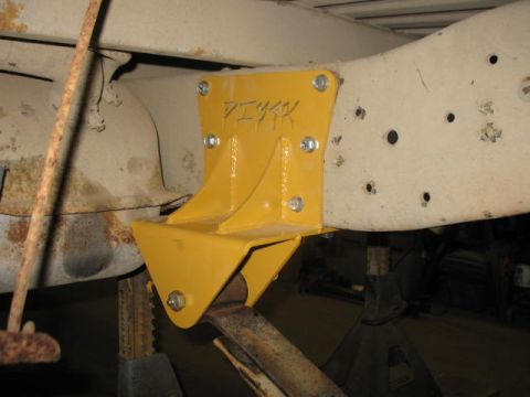 1989 Chevrolet C/K Pickup - A yellow bracket, possibly a custom part, is bolted to the frame of a vehicle. The text 'PIYAK' is visible on the bracket.