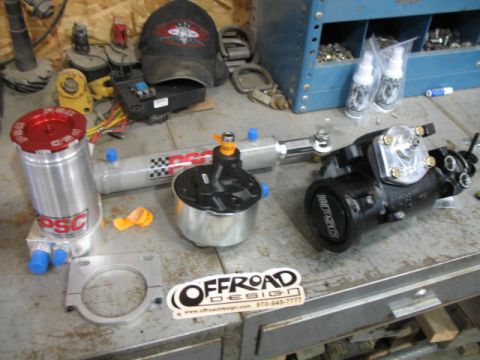 1989 Chevrolet C/K Pickup - Various automotive parts, including a reservoir and steering gear, are laid out on a workbench.