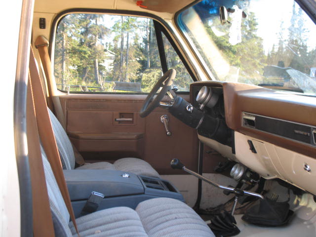 Pickup truck interior with brown dashboard, cloth seats, and floor shifter