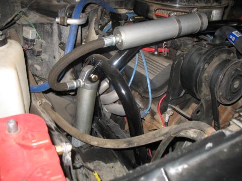 1989 Chevrolet C/K Pickup - Close-up view of an engine bay showing various hoses, wiring, and engine components, including a silver canister and black tubing.