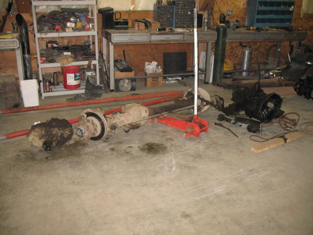 Drivetrain parts including axles and a transmission on a concrete garage floor