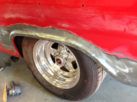 1964 Ford Fairlane - The rear wheel well of a car is shown with metalwork being done on the fender.