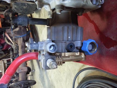 1995 Ford Bronco - Close-up of a pressure washer pump assembly, a blue fitting and red tubing.