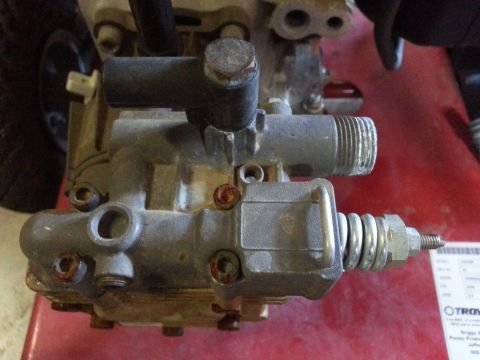 1995 Ford Bronco - Close-up of a pressure washer pump assembly, showing various metal components and connections.