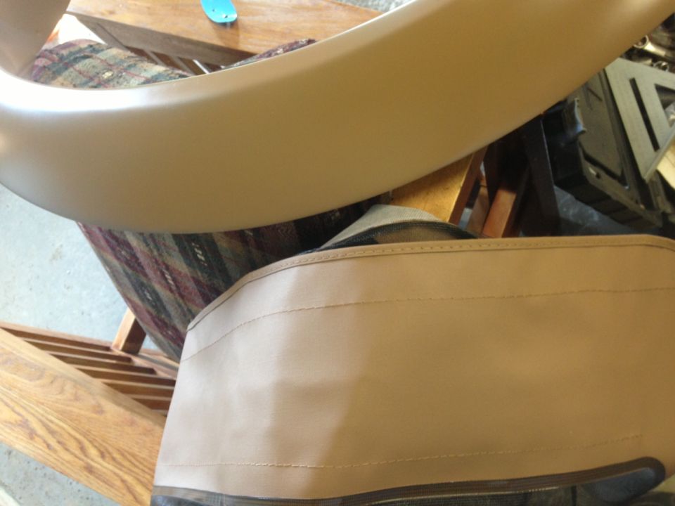 Tan vehicle interior trim panel and stitched upholstery in a garage workshop