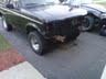 1994 Ford Bronco - A black pickup truck sits on a driveway with significant damage to its front end, revealing the radiator and other components.