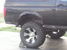 1994 Ford Bronco - Close-up of the rear wheel and fender of a black SUV, possibly lifted.