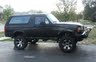 1994 Ford Bronco - A black Ford Bronco is parked outdoors, showing its side profile with aftermarket modifications.