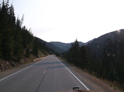 2009 Kenworth T800 - A view from a vehicle traveling on a highway through a forested mountain landscape.