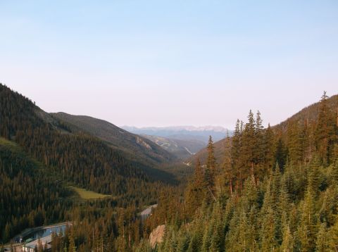 2009 Kenworth T800 - A vast mountain valley is captured from above, showing a winding road and a tranquil body of water.