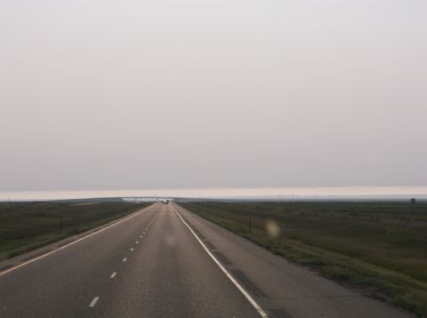 2009 Kenworth T800 - A long, straight highway disappears into a hazy horizon under a pale sky.